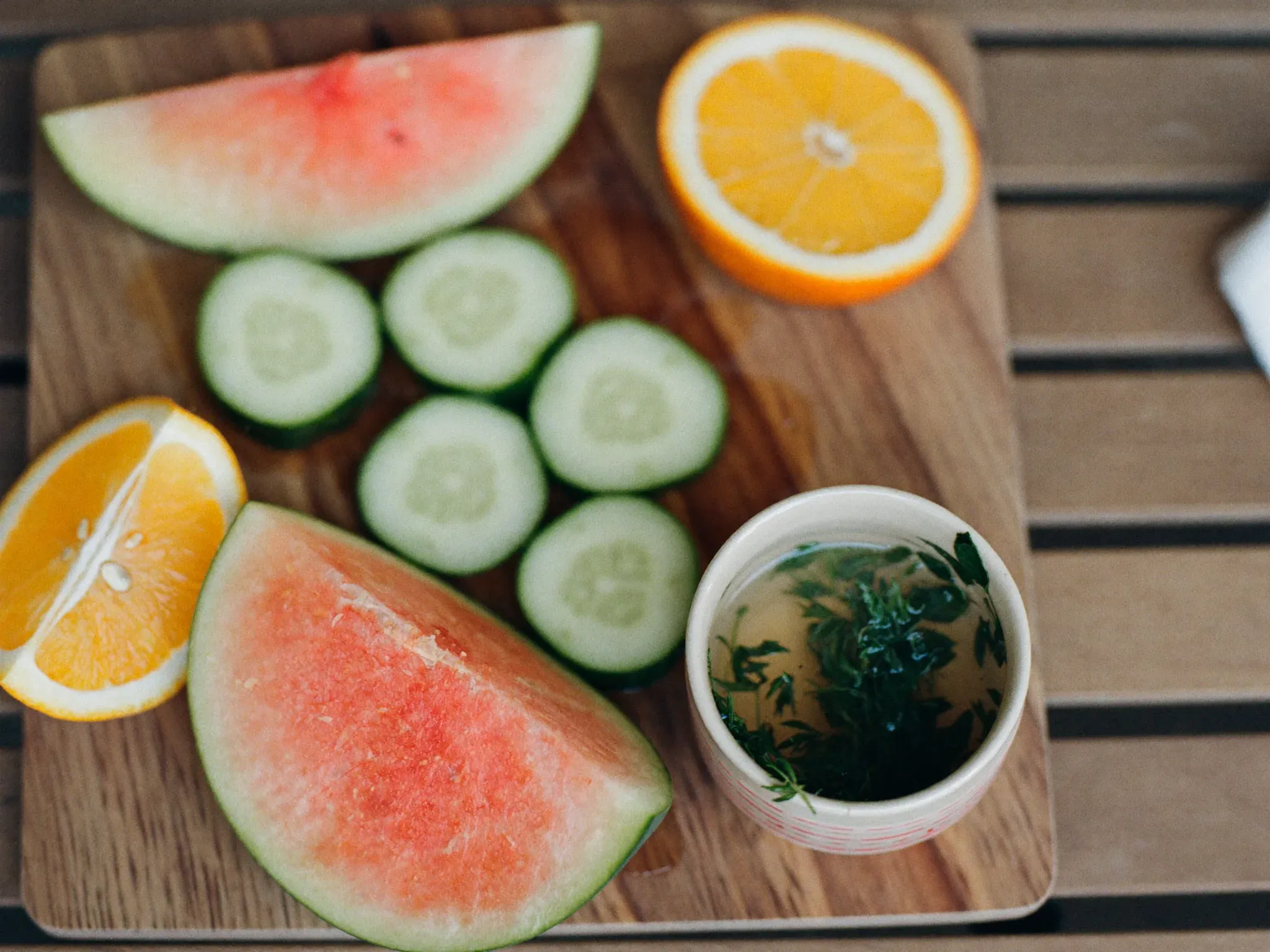 http://Tabla%20con%20sandía,%20pepino,%20naranja%20y%20una%20taza%20de%20infusión%20de%20hierbas,%20alternativas%20para%20hidratarse.