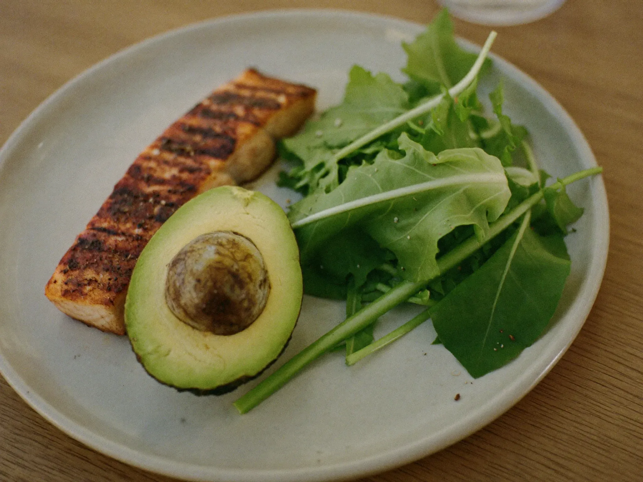 http://Plato%20con%20salmón%20a%20la%20plancha,%20palta%20y%20hojas%20verdes%20frescas%20sobre%20una%20mesa%20de%20madera.