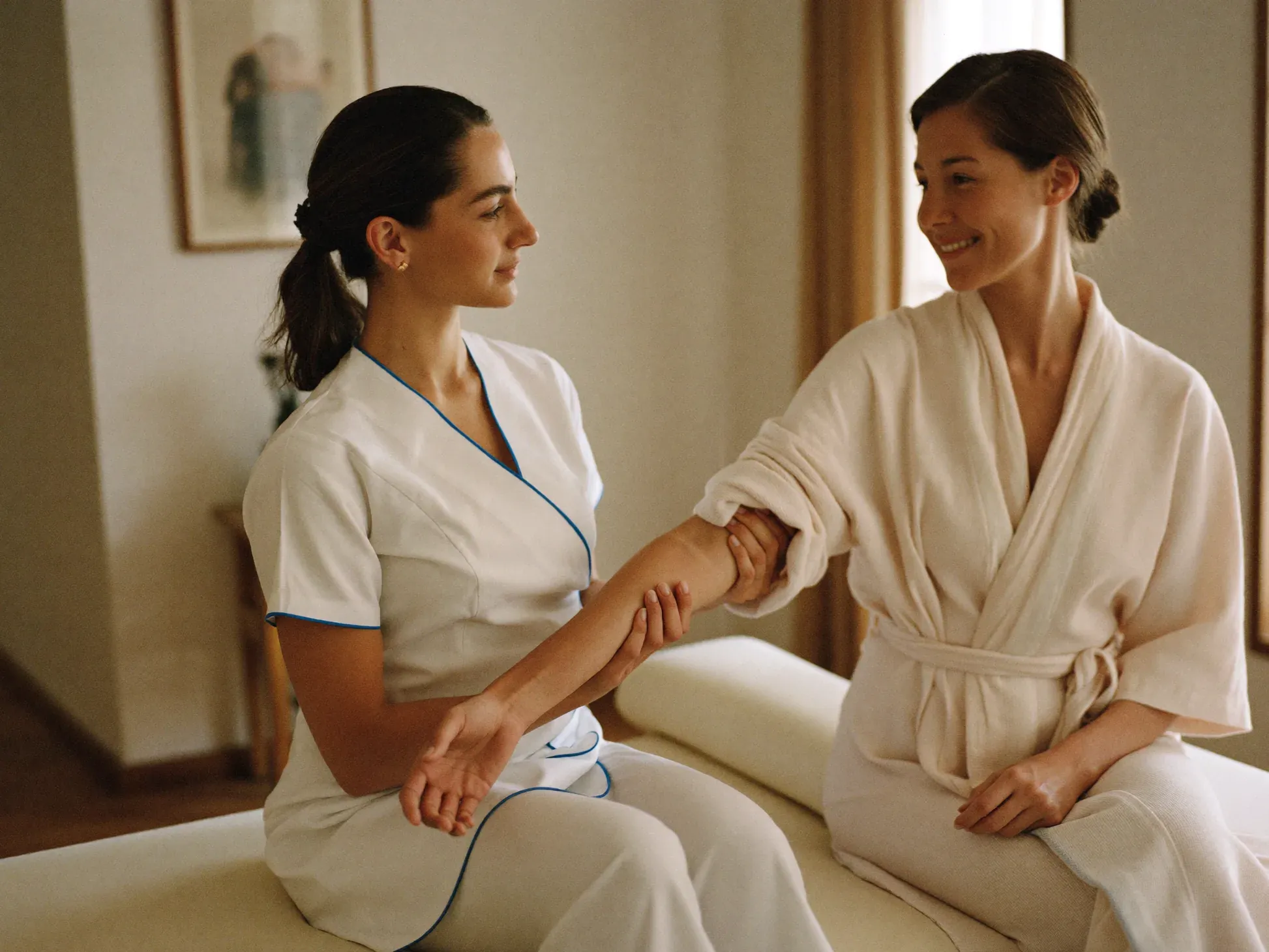 http://Terapeuta%20de%20NCA%20trabajando%20el%20brazo%20de%20una%20clienta%20en%20bata%20durante%20una%20sesión%20de%20drenaje%20linfático.